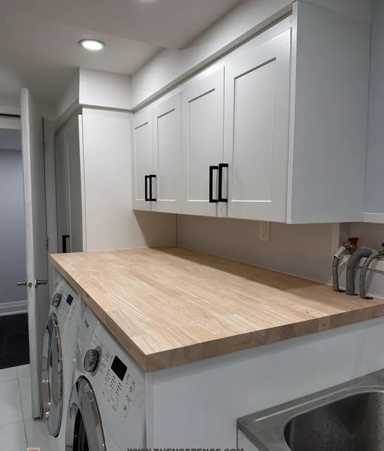 Modern laundry room with white cabinets and wooden
countertop